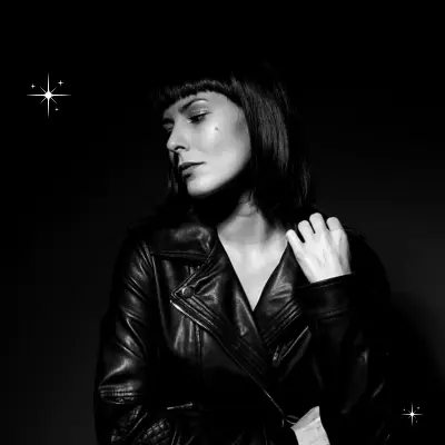 A mordern, confident woman is standing wearing a black jacket elevating her style.